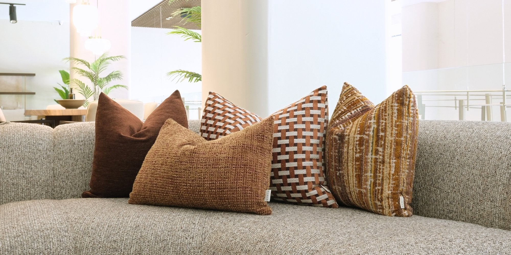 Remon Home dekoratif kırlent kombinasyonu; kahverengi, tarçın ve toprak tonlarında dokulu ile geometrik desenli premium kırlentlerle gri koltuk üzerinde sıcak ve modern salon dekorasyonu sunuyor.